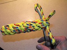 a person is holding a crochet hook with yellow and red yarn on it