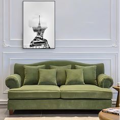 a green couch in front of a white wall with the eiffel tower on it