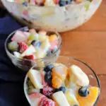 two bowls filled with fruit salad on top of a wooden table next to another bowl