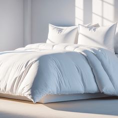 an unmade bed with white sheets and pillows