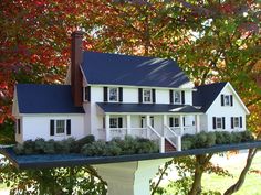 a model house is shown in front of some trees with red and green leaves on it