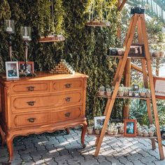 an old wooden ladder stands next to a dresser with pictures on it and other items