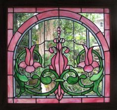 a stained glass window with pink flowers and green leaves on the bottom, surrounded by trees