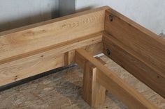 a wooden bench sitting on top of plywood flooring next to a cement wall