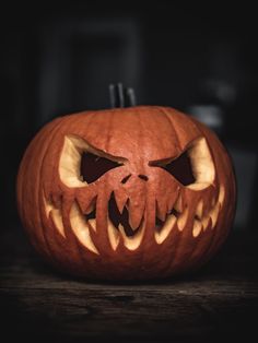 a carved pumpkin with teeth and fangs on it's face, sitting on a table