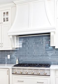 a stove top oven sitting inside of a kitchen next to white cabinets and cupboards