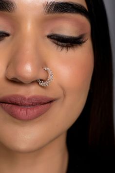 a close up of a woman with a nose ring on her nose and an earring in the shape of a crescent