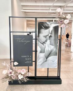 a black and white photo frame with flowers on the floor in front of an advertisement