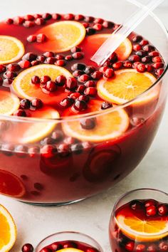 a bowl filled with oranges and cranberries on top of a white table