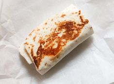 a piece of food that is sitting on some white paper with brown and orange spots