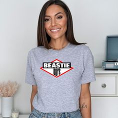 a woman standing in front of a white wall wearing a t - shirt with the words beastie on it