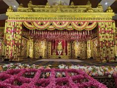 an elaborate decorated stage with pink flowers in the foreground and gold decorations on either side