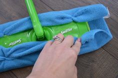 a person is cleaning the floor with a green mop and blue towel on it