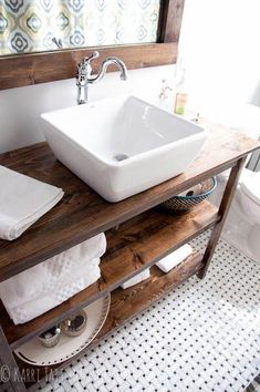 a white sink sitting on top of a wooden counter next to a toilet in a bathroom