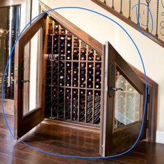 an open wine cellar in the corner of a room with wooden floors and stairs leading up to it