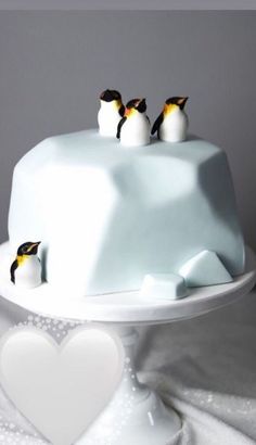 three penguins on top of a white cake