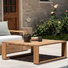 a wooden coffee table sitting on top of a patio next to a white couch and potted plant