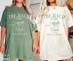 two women standing next to each other in front of a wall with the back club t - shirts on