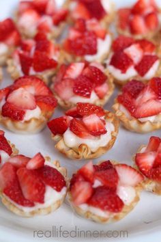 small desserts are arranged on a plate with strawberries in the middle and whipped cream on top