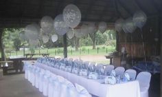 the tables are set up with white tablecloths and silver balloons hanging from the ceiling