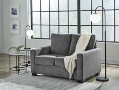 a living room scene with focus on the grey couch and white throw blanket, along with two side tables