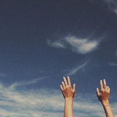 two hands reaching up into the sky to catch a frisbee