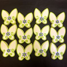 butterfly shaped cookies with blue and green decorations on them, sitting on a black surface