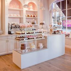 a display case filled with lots of cakes and cupcakes on top of glass shelves