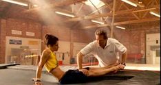 a man and woman sitting on top of a trampoline in an indoor gym