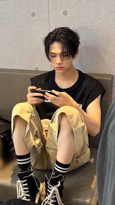 a young man sitting on a bench looking at his cell phone while wearing black socks