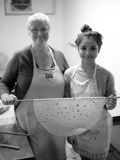 two women in aprons are holding an object