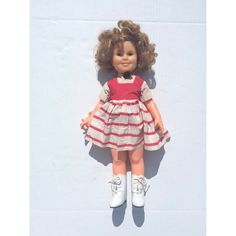 a doll is laying on the ground with her hair blowing in the wind, wearing a dress and white tennis shoes