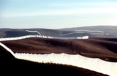 a long white fence in the middle of a field