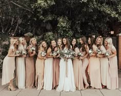 a group of women standing next to each other holding bouquets in their hands and smiling at the camera