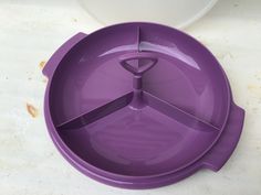 a purple plastic bowl with two spoons in it