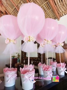 pink and white balloons are in buckets with bows on the top, along with other decorations