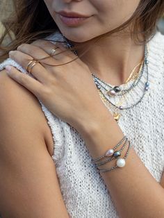 "A tribute to calming seas, this beaded pearl bracelet is a model example of Hawaii's allure. Accented with gold-filled details, this beaded beauty features scads of tiny peacock pearl beads and a single baroque freshwater pearl in a prismatic shade of white alabaster. ✦ DETAILS ✦ ✧ Name: Kaimalie (KAEE ma LEE eh) - Calm sea, quiet sea. ✧ Adjustable Length from: 6.5\"-8\". ✧ 1 White Baroque Freshwater Pearl. ✧ 2-3mm Peacock Freshwater Pearls. ✧ 14kt Gold Filled Components, Extender, and Clasp. ✧ Pearl Bead Bracelet, Black Pearl Bracelet, Tahitian Pearl Bracelet, Black Peacock, Peacock Pearls, Calm Sea, Gold Pearl Bracelet, Peacock Pearl, Gemstone Hoop Earrings