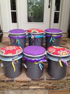 six buckets sitting on the ground in front of a door with ribbons tied around them