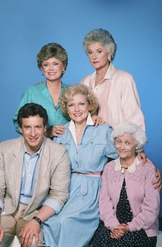 the golden girls are posing for a family portrait in front of a blue wall with their arms around each other