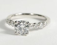 an engagement ring with three stones on the side and one stone in the middle, sitting on a white surface