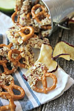 apples and pretzels are sitting on a towel next to an apple slice with caramel