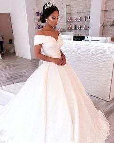 a woman wearing a white wedding dress standing in front of a counter