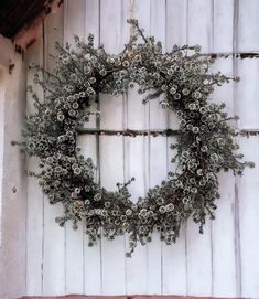 a wreath is hanging on the side of a white building with snow flakes around it