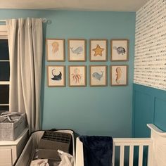 a baby's room with blue walls and pictures on the wall, including a crib