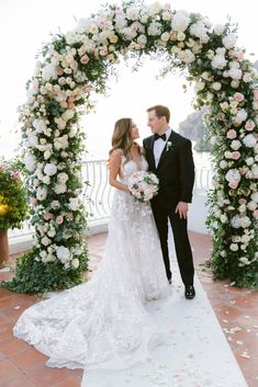 a bride and groom kissing in front of a floral arch