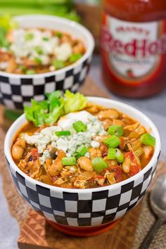 two bowls filled with chili and beans on top of a cutting board