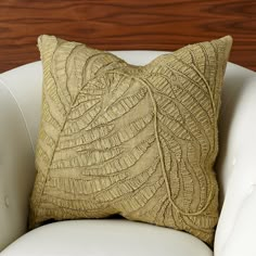 a close up of a pillow on a chair with a wooden wall in the background