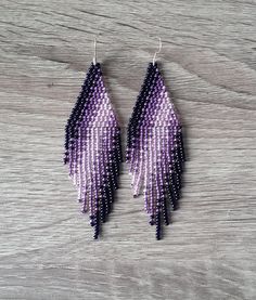 purple and black beaded earrings with fringes on wooden background, close up photo