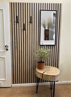 a small table with a potted plant on it in front of a striped wall