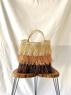 a handbag sitting on top of a wooden table next to a white wall and black legs